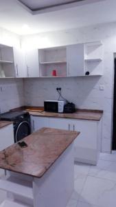 cocina con armarios blancos y encimera en Motalvin Court, en Lagos