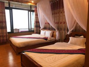 a bedroom with two beds with curtains and a window at Sau Meo Mountain View in Sa Pa