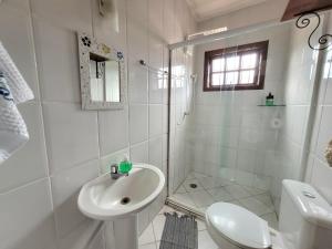 y baño blanco con lavabo y ducha. en Casa para temporada em Ilhabela, en Ilhabela