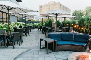 eine Terrasse mit Stühlen, Tischen und Sonnenschirmen in der Unterkunft Le Méridien Chicago - Oakbrook Center in Oak Brook