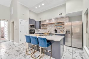 a kitchen with a white counter and blue bar stools at Modern Accessible Houston Gem Jacuzzi & Air Hockey 6Beds in Houston