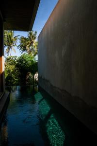 una piscina d'acqua accanto a un edificio con palme di Langit Pitu Villas a Ketewel