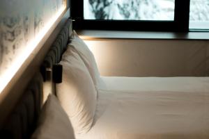 a bed with white pillows in a bedroom with a window at Hotel Boutique Anoma in Sarajevo