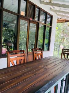 een houten tafel en stoelen in een kamer met ramen bij Pepper Garden Resort in Ella