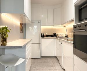 a kitchen with white cabinets and a refrigerator at Full Circle Apartments in Jindabyne