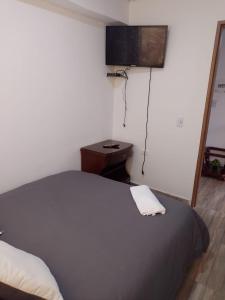 a bedroom with a bed and a television on the wall at VERDUN ROOMS in Bogotá