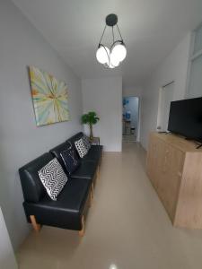 Transient in Bria Homes في جنرال سانتوس: غرفة معيشة مع أريكة جلدية سوداء وتلفزيون