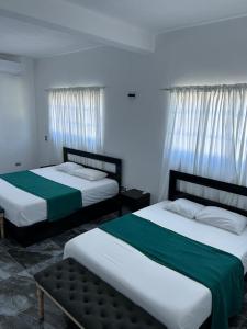 two beds with green and white sheets in a room at Villa Grecko Place in Jarabacoa