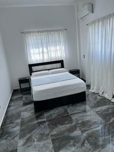 a bedroom with a large bed with white curtains at Villa Grecko Place in Jarabacoa