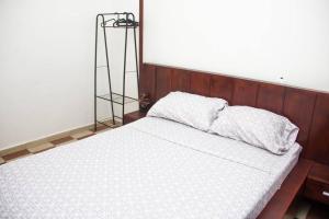 1 dormitorio con cama blanca y cabecero de madera en Appartement Urbain & Confortable en Cotonú