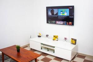 a living room with a white cabinet and a tv on the wall at Appartement Urbain & Confortable in Cotonou
