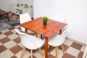 a wooden table with white chairs and a potted plant at Appartement Urbain & Confortable in Cotonou