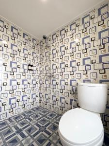 a bathroom with a toilet and a tile wall at Ciater Dream Village in Cicadas