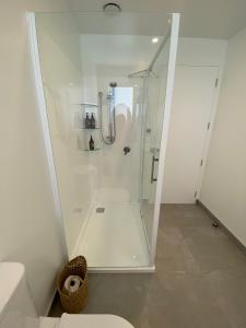 una ducha con puerta de cristal en un baño en Lake Views - new apartment with room to relax, en Wanaka