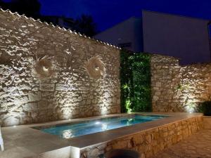 a stone wall with a swimming pool in front of a building at Maison en pierre avec piscine, 6 couchages, située au cœur de Mallemort, Provence. - FR-1-658-25 in Mallemort