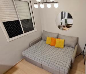Sofá con 2 almohadas amarillas en una habitación con espejo en Aconchegante Apartamento no coração de Santo Amaro, en São Paulo