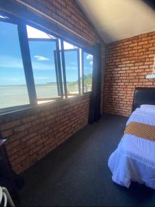 a bedroom with a brick wall and a bed and a window at SB SUNSET KUCHING in Kuching