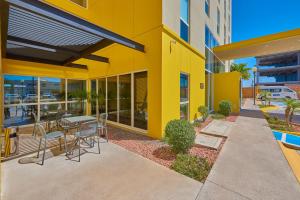 a yellow building with a table and chairs on a patio at City Express by Marriott Tijuana Otay in Tijuana