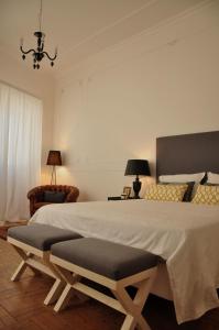 a bedroom with a large bed and a chair at Casa18.55 - Time with history in São Brás de Alportel