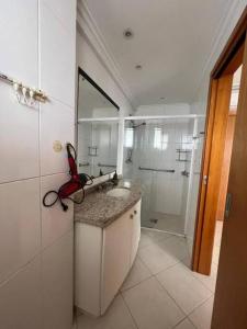 a white bathroom with a sink and a shower at Apartamento em Balneário com vista para o mar in Balneário Camboriú