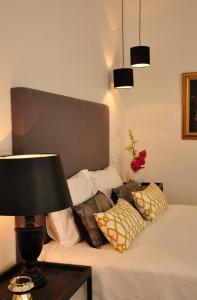 a bed with pillows and a table with a lamp at Casa18.55 - Time with history in São Brás de Alportel