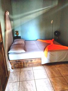 um quarto com uma cama com um cobertor laranja em Anluka-House em Puerto Jiménez