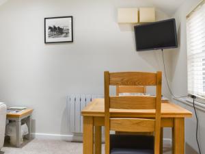 a desk with a chair and a television on a wall at The Six Bells Barn in Sudbury