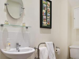 a white bathroom with a sink and a mirror at The Six Bells Barn in Sudbury