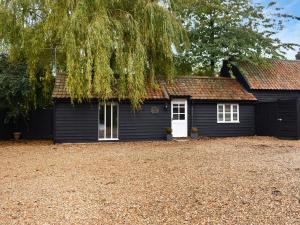 a black house with a white door and a tree at The Six Bells Barn in Sudbury