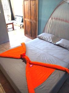 a bed with an orange blanket on top of it at Anluka-House in Puerto Jiménez
