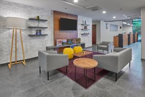 a lobby with chairs and a table and a tv at City Express by Marriott Tapachula in Tapachula