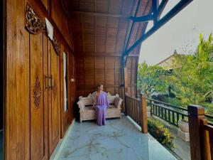 a woman sitting on a couch on a porch at Innora Jungle Resort And Spa in Nusa Penida