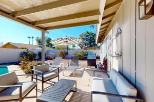 patio z krzesłami, stołami i parasolem w obiekcie Grand Palms w mieście Scottsdale