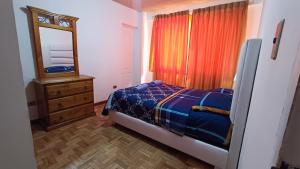 1 dormitorio con cama, tocador y espejo en Acogedor y Céntrico Depto Av. Libertador Cala Cala, en Cochabamba