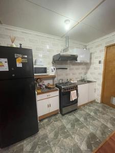 a kitchen with a black refrigerator and a stove at Cabañas Porvenir Tierra del Fuego in Porvenir