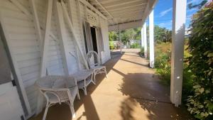 eine Veranda eines weißen Hauses mit Korbstühlen in der Unterkunft Ribbonwood Bed & Breakfast, Emu Park Qld in Emu Park