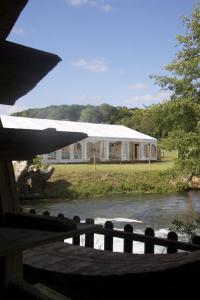 un edificio bianco con un fiume di fronte di Logis - Hôtel & Restaurant Moulin Des Forges a Saint-Omer-en-Chaussée