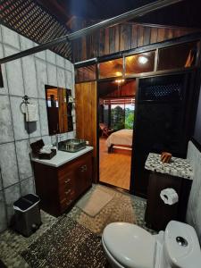 a bathroom with a toilet and a sink and a bedroom at Pitangus Lodge in Chachagua