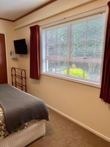 een slaapkamer met een bed en een raam met rode gordijnen bij Carly’s Place in Rotorua