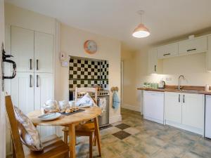 a kitchen with a table and a kitchen with white cabinets at 3 Bed in Llandrindod Wells 65885 in Llanbadarn-fynydd