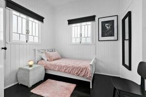 a small bedroom with a bed and two windows at Retro on walker in Maryborough