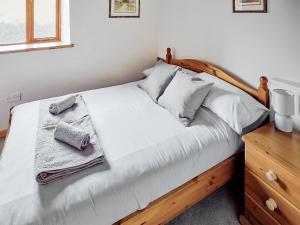 a bedroom with a white bed with a wooden headboard at Mill Meadow Cottage in East Down