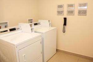 a laundry room with two washers and a phone on the wall at Courtyard by Marriott San Jose Airport Alajuela in Alajuela City
