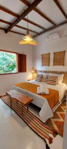 una camera con un grande letto e un tavolo di Afeto Caraíva a Caraíva