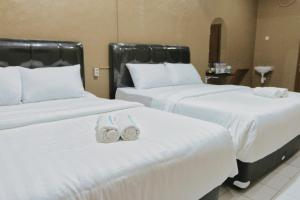 dos camas con zapatos de boda en una habitación de hotel en Hotel Solaris Malioboro, en Jetis