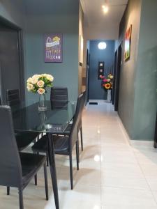 ein Esszimmer mit einem Glastisch und schwarzen Stühlen in der Unterkunft Casa Inderaloka Pantai Batu Buruk in Kuala Terengganu