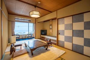 ein Wohnzimmer mit einem Tisch, Stühlen und einem Fenster in der Unterkunft Shorenkan Yoshinoya in Kyōtango
