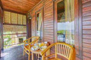 a dining room with a table and chairs on a porch at Song Cang Bungalow in Nusa Penida