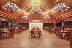 un comedor con mesas, sillas y lámparas de araña en Griya Persada Convention Hotel & Resort Bandungan, en Bandungan