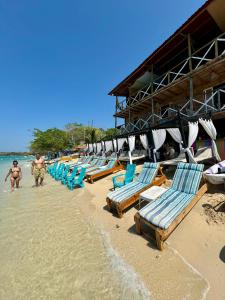 eine Reihe von Liegestühlen und Sonnenschirmen am Strand in der Unterkunft Tequila SunBeach Baru Eco-Hotel in Barú
